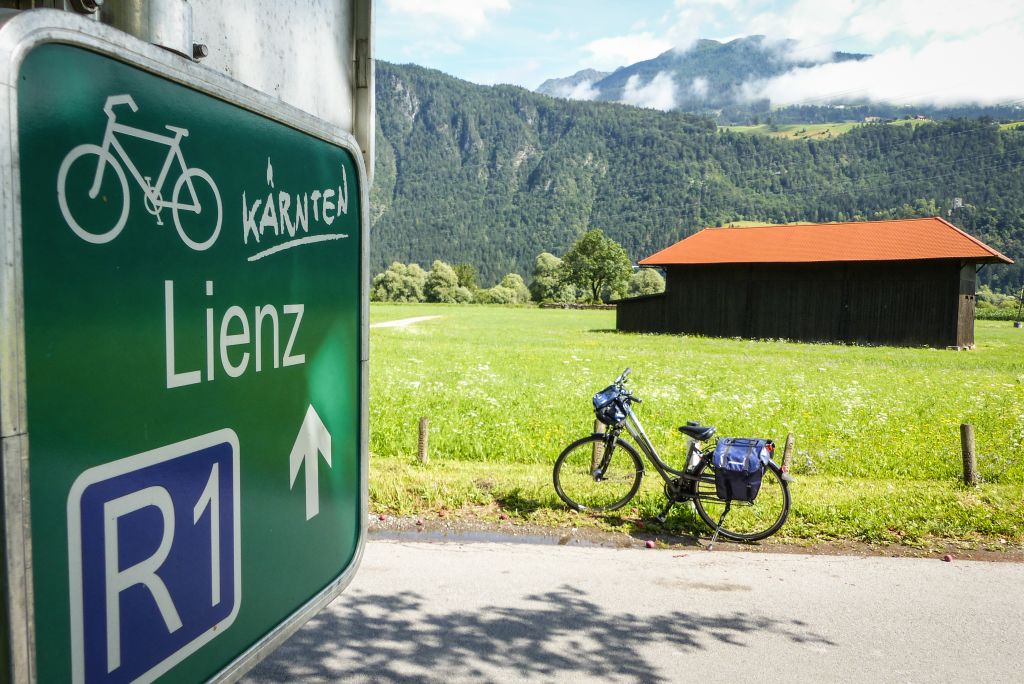 Bici in sosta in contesto alpino con casa tipica in legno e prati verdi, Austria