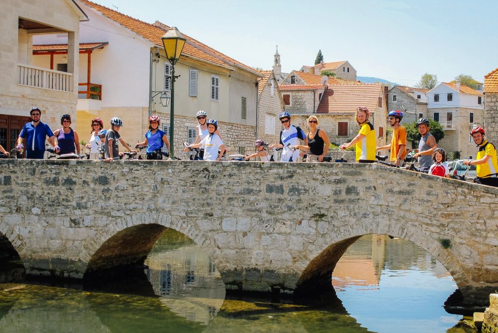 Ciclisti in vacanza con Girolibero sul ponte di una città in Croazia. Vacanze in gruppo.