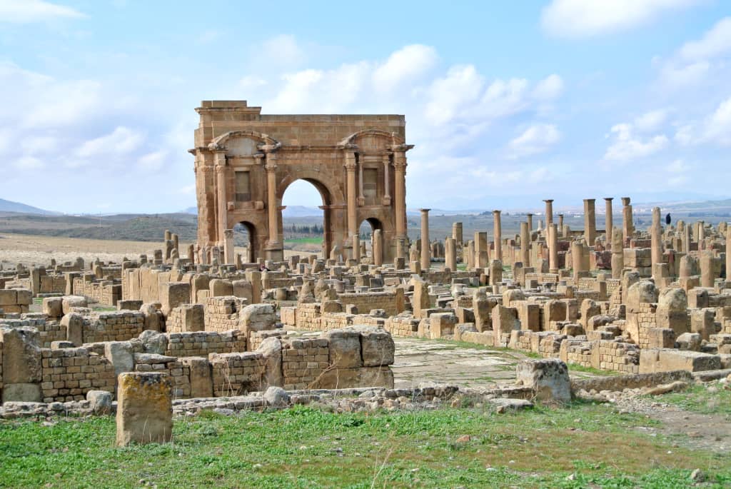 Antiche rovine della città romana di Timgad con l’arco di Traiano sullo sfondo.