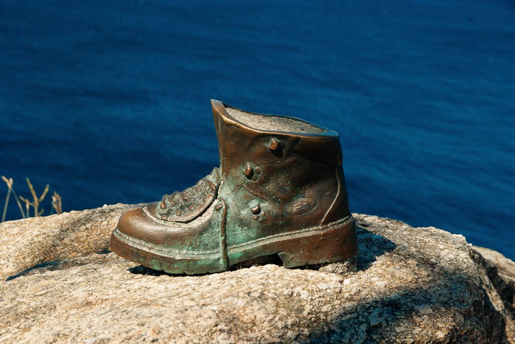 Scultura di uno scarpone in bronzo posta su una roccia, simbolo del percorso del pellegrinaggio a Santiago.