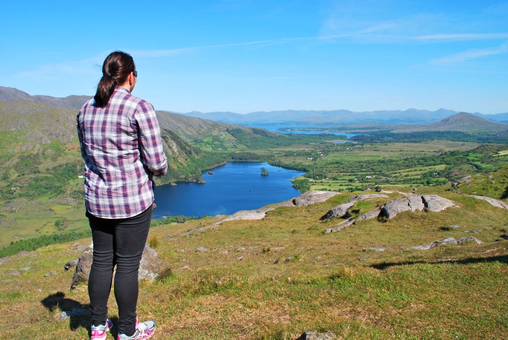 Escursionista che ammira un lago e le colline verdi lungo il percorso tra Cork e Kerry.