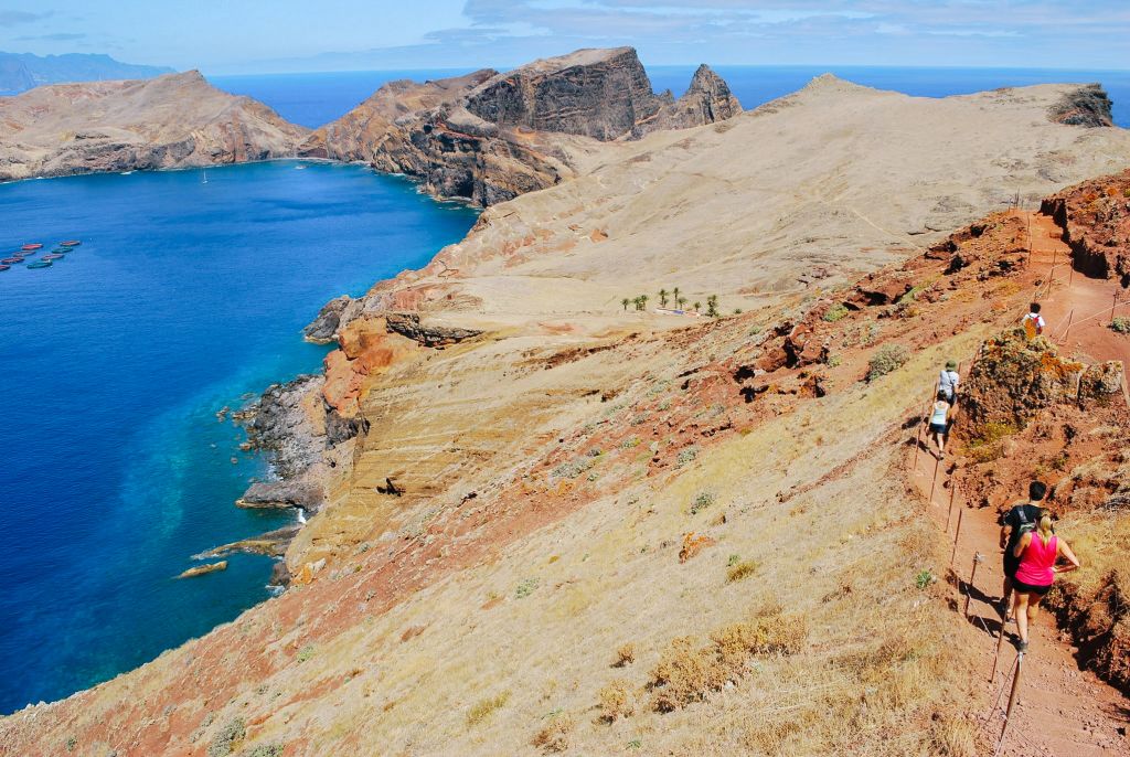 Escursionista su un sentiero costiero roccioso con vista sull'oceano, Madeira, Portogallo.
