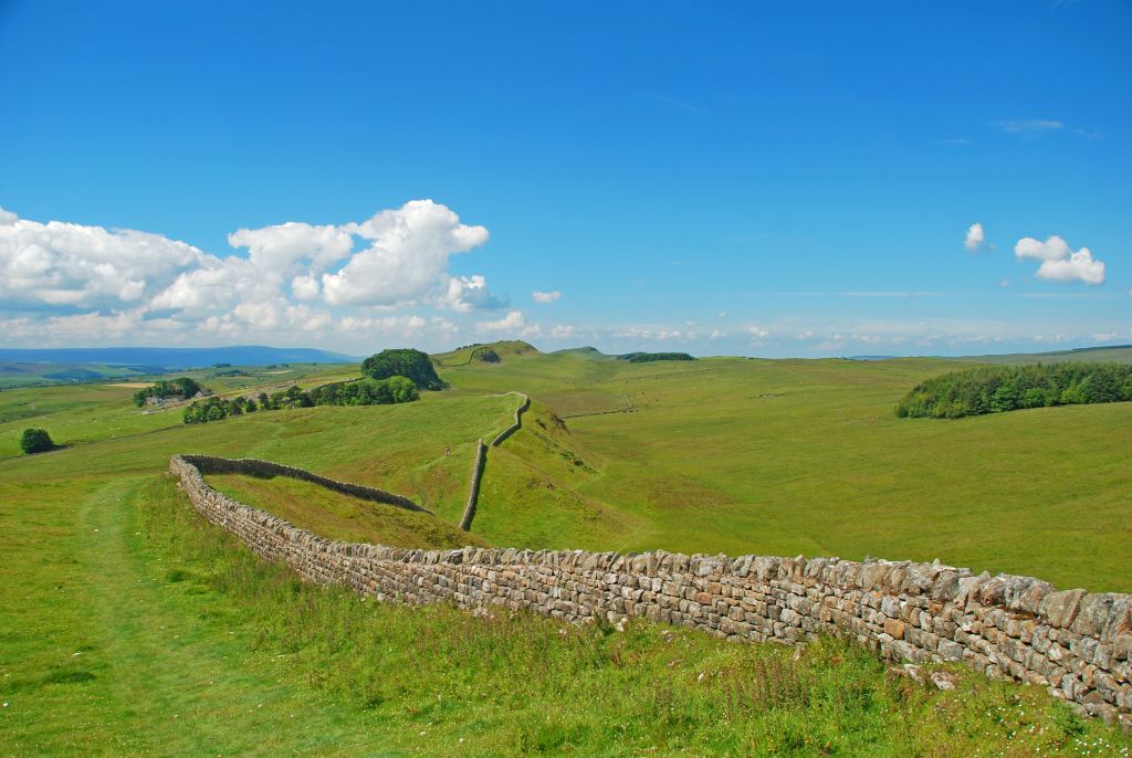 Mura romane che attraversano un paesaggio rurale verdeggiante.