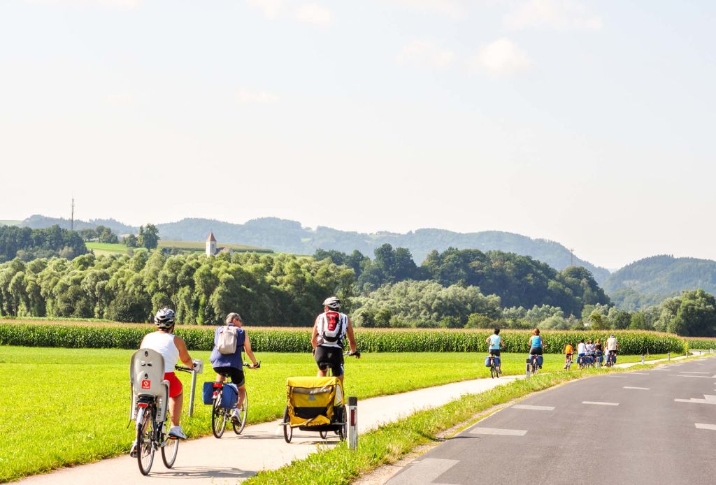 Coppia in bicicletta attraverso i campi verdi della Baviera, Germania.