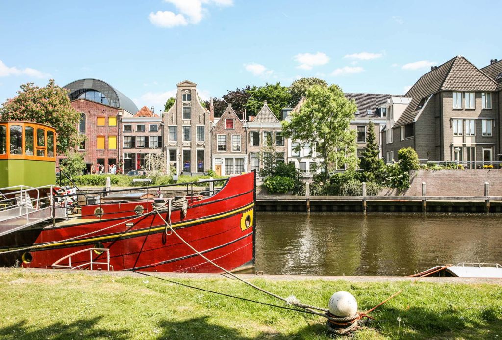 Rotes Boot, das an einem Haus an einem Kanal in Utrecht, Niederlande, angelegt ist