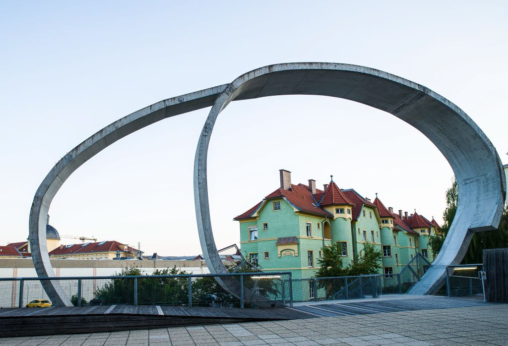 Complesso di case azzurre con tetto rosso viste attraverso un arco lungo la ciclabile del Danubio, tra Linz e Vienna, Austria