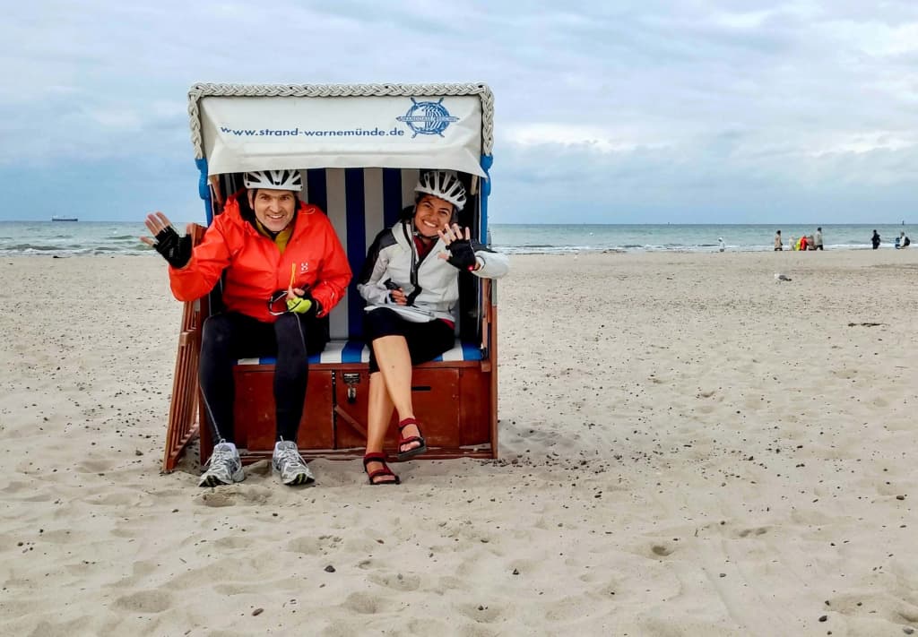 due ciclisti sorridono e salutano l'obiettivo durante una pausa lungo la ciclabile Berlino Copenaghen