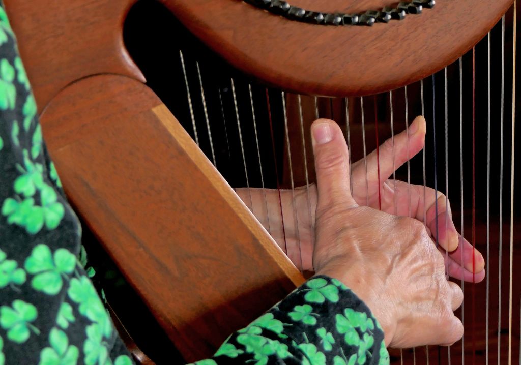 Dettaglio di mani che suonano un’arpa celtica, simbolo della musica tradizionale irlandese.