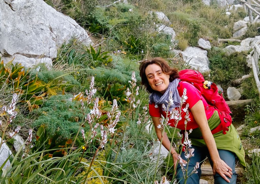 Guida ambientale escursionistica su un percorso trekking, intenta a studiare la vegetazione del luogo, viaggiare con guida gae