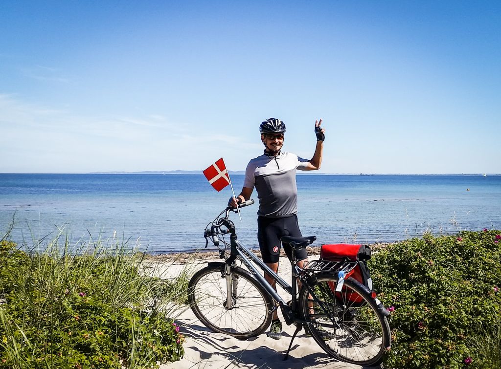 Ciclista con bandiera danese lungo la costa, Copenaghen, Danimarca in bicicletta con "Girolibero"