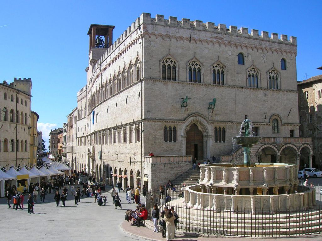 Palazzo dei Priori a Perugia, Umbria, Italia, con turisti nella piazza centrale.