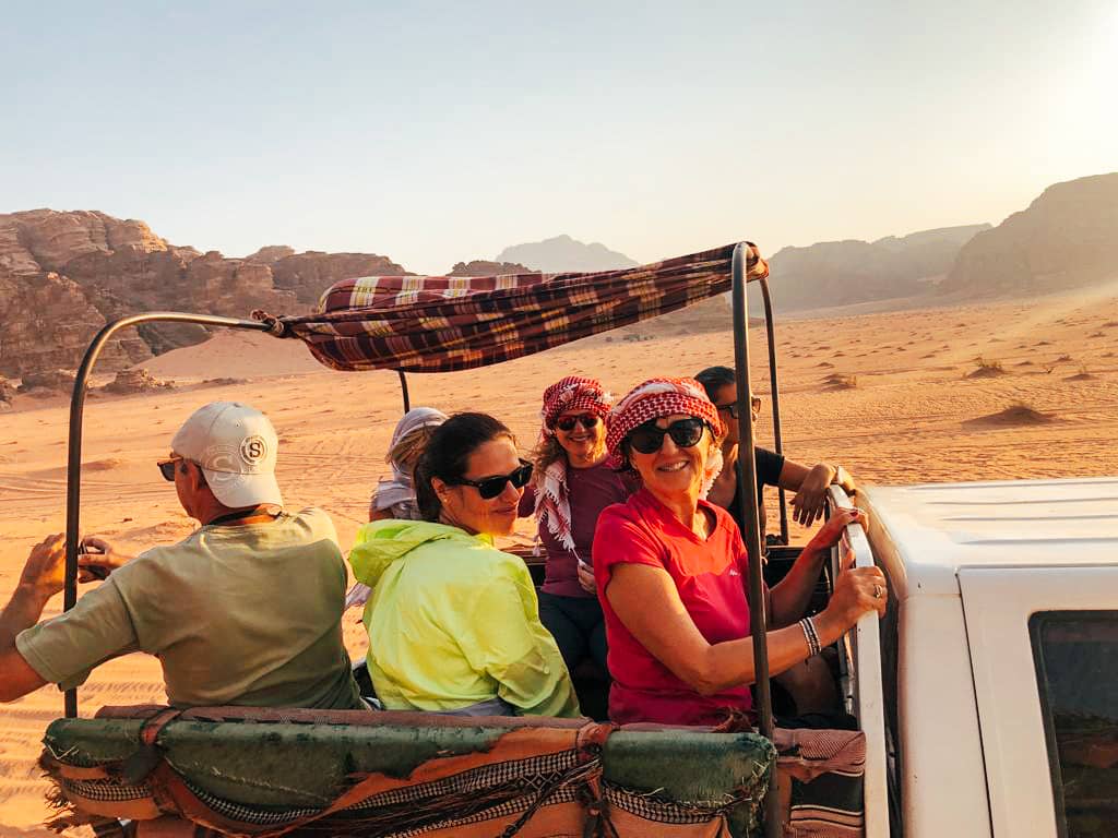 Jeep tour nel deserto rosso di Wadi Rum al tramonto con viaggiatori sorridenti, avventura giordana