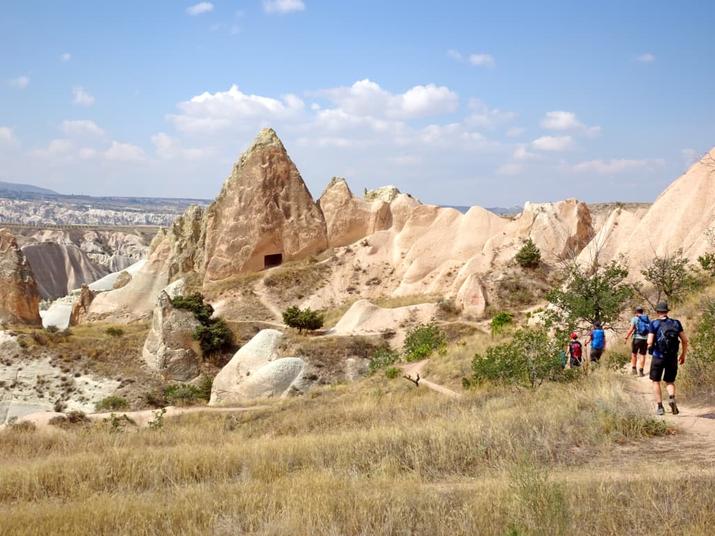 Gruppo di camminatori su un sentiero tra un paesaggio della Cappadocia e i camini delle fate