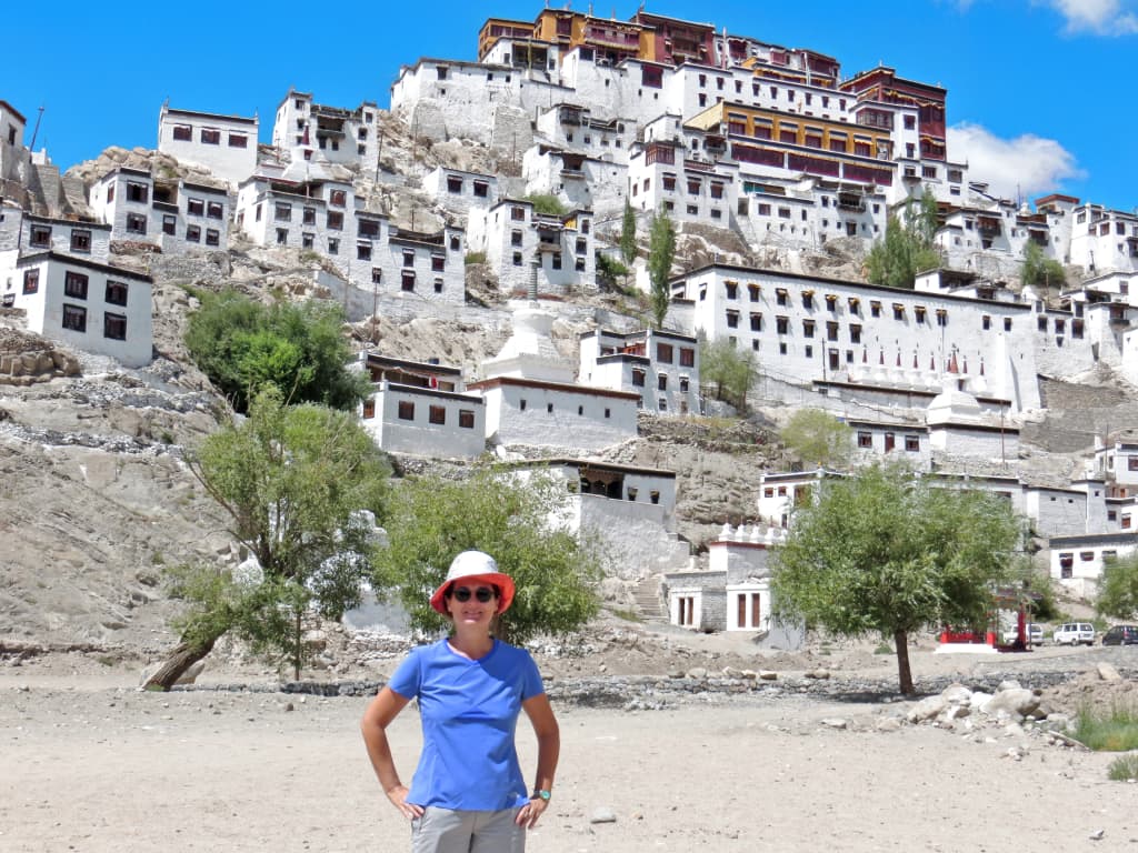 Monastero Thiksey vicino Leh, Ladakh: complesso buddista arroccato su una collina, con turista in primo piano.