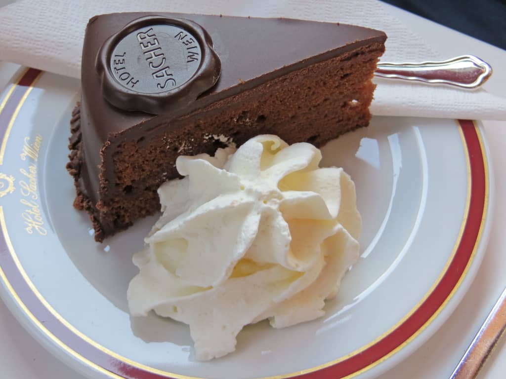 Fetta di Sachertorte viennese con panna montata servita su piatto decorato in una caffetteria storica di Vienna