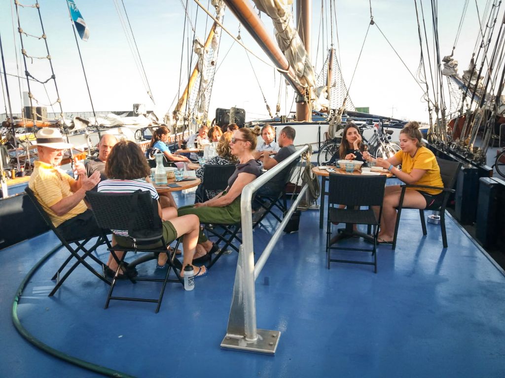 Touristen sitzen an Bord eines Segelschiffs auf den friesischen Inseln, Rad- und Bootsfahrt in Holland