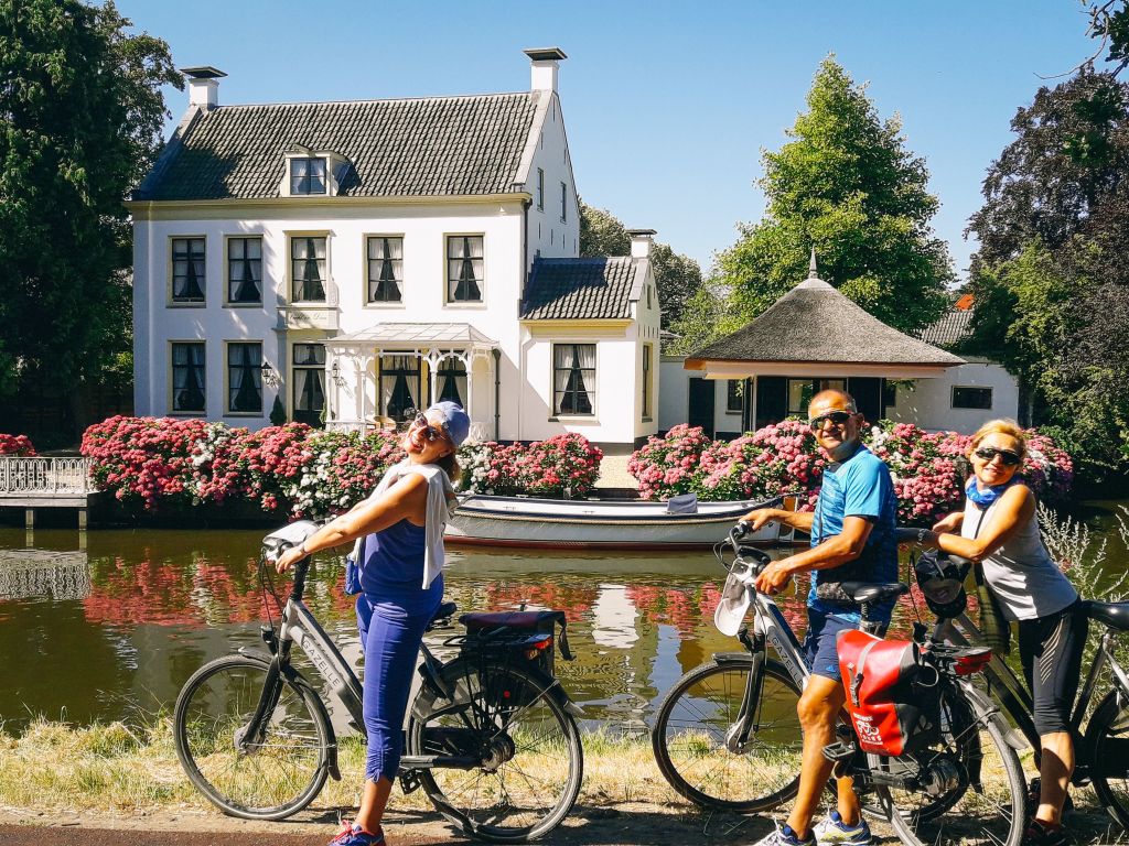Famiglia in bicicletta in viaggio con "Girolibero" vicino a un canale nel villaggio di Giethoorn, Paesi Bassi.