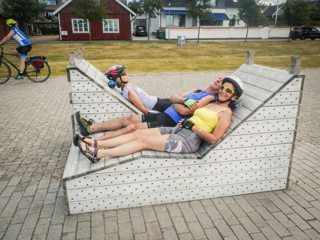 Coppia di ciclisti sdraiati su una panchina urbana moderna, Copenaghen, Danimarca, viaggi in bici organizzati "Girolibero"