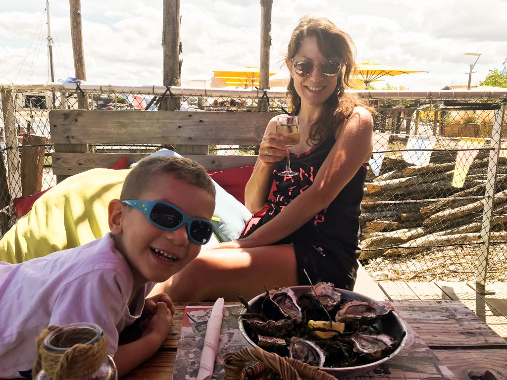 Famiglia seduta al tavolo che si scatta una foto al tramonto, con il mare in lontananza.