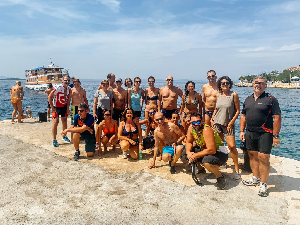 Gruppo di turisti in posa su una spiaggia della Croazia, vacanze in bici e barca