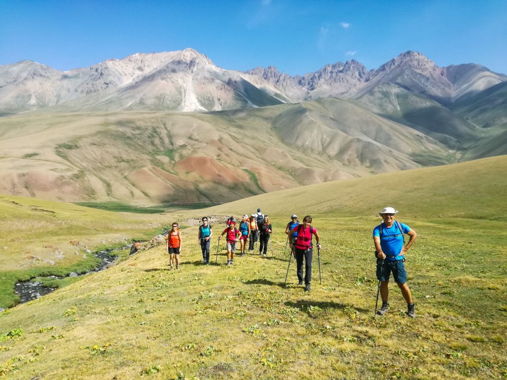Gruppo di escursionisti in vacanza con Girolibero cammina su una verde vallata con montagne innevate sullo sfondo in Kirghizistan. La terra delle aquile: tra natura mozzafiato e tradizioni millenarie Fabio Bianchi