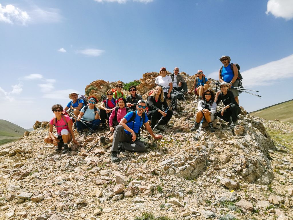 Gruppo di escursionisti seduti su una cima rocciosa, trekking con accompagnatore in Kirghizistan