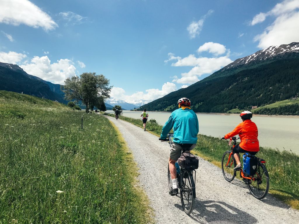 Cyclists riding on a bike path between green fields, Italy.