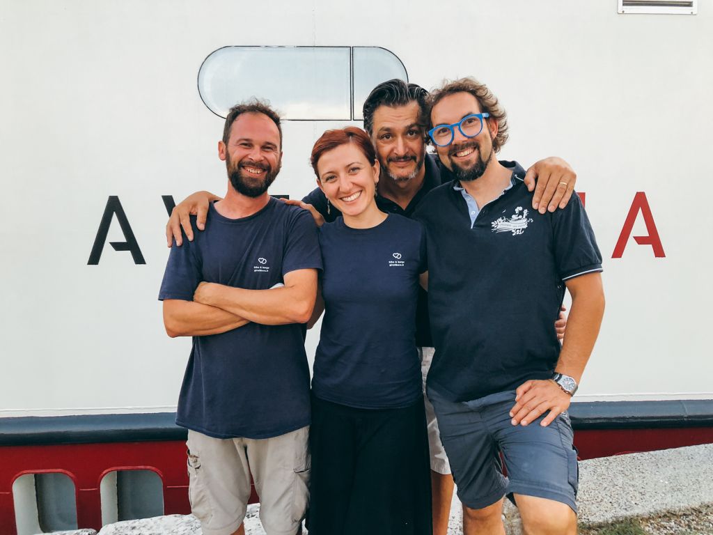 Quattro persone sorridenti davanti alla barca Ave Maria