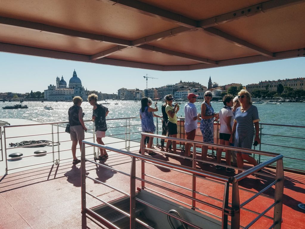 A group of people on board a Girolibero boat sail through the lagoon near Punta della Dogana