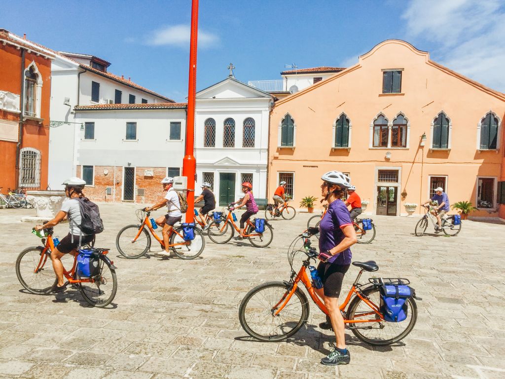 Square with cyclists and traditional architecture in Italy.