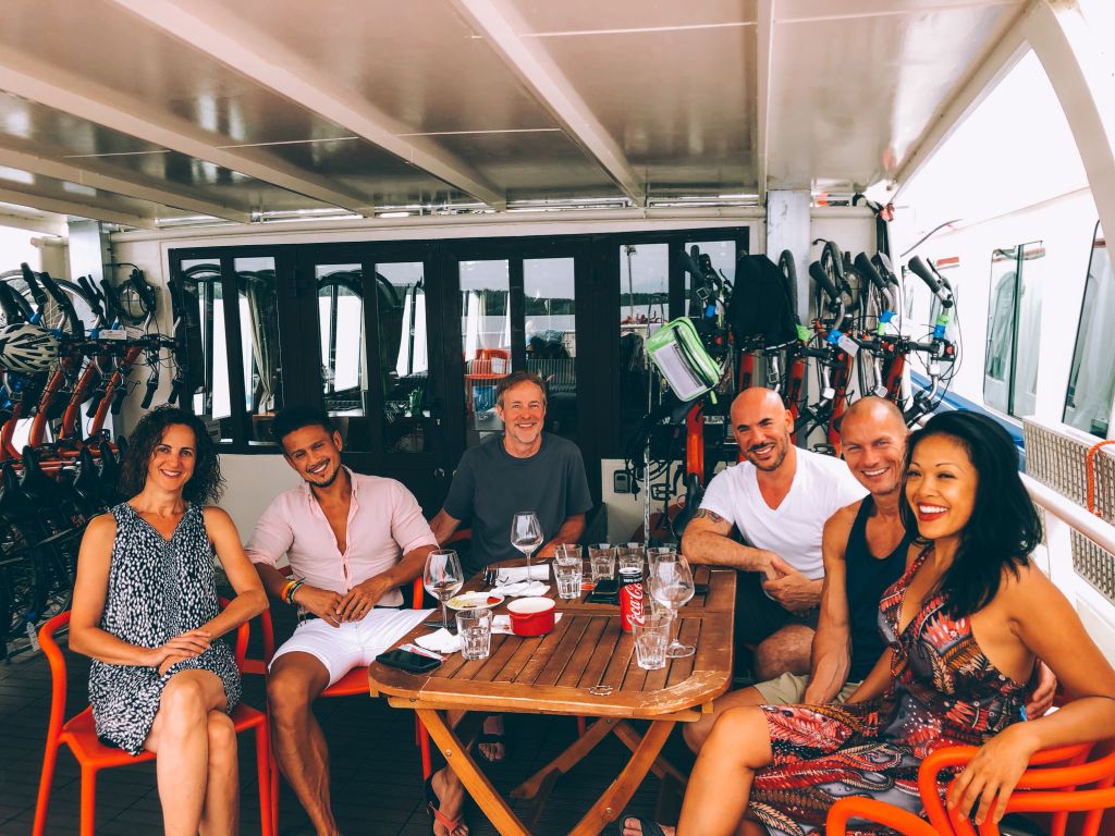 Group of friends sit outdoor during a barge trip on the Rhône River, Provence, France.