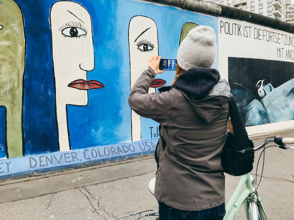 Persona che scatta foto al murale di East Side Gallery, Berlino, Germania.