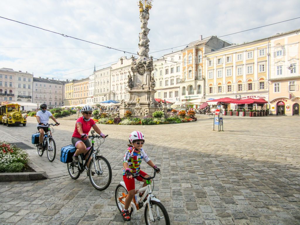 Famiglia con bambino con caschetto, piazza principale del centro storico di Linz, vacanza in bici, Austria