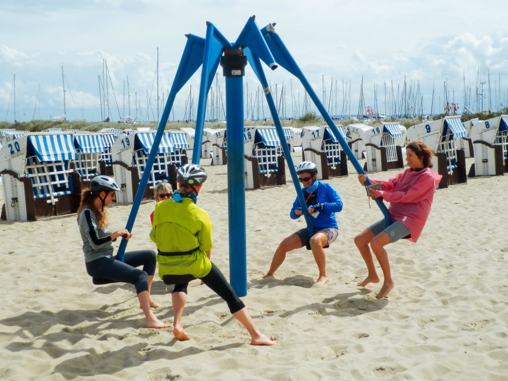Gruppo di amici che giocano su una giostra in una spiaggia sul Mar Baltico, vacanze in bicicletta "Girolibero"