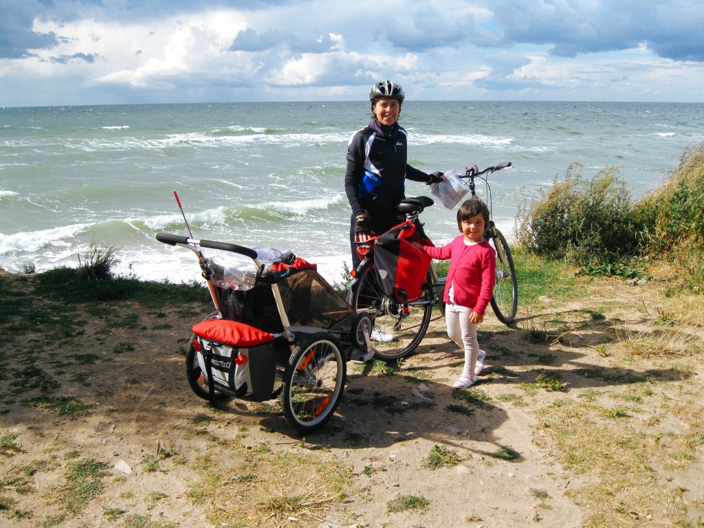 Famiglia di cicloturisti, bici con carrellino, viaggio per famiglie, paesaggio brullo, mar Baltico, Germania