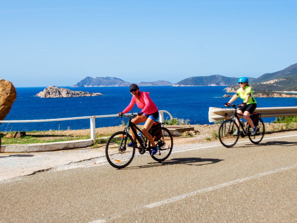 Gruppo di ciclisti su una strada costiera in Sardegna con vista sul mare
