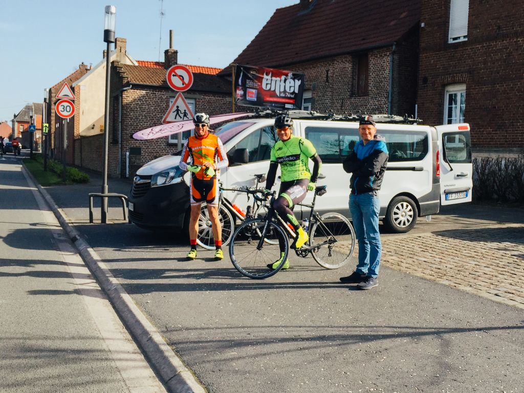 Ciclisti in sosta davanti a una casa storica in mattoni durante la Parigi-Roubaix.