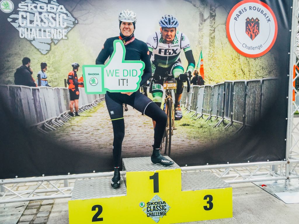 Due ciclisti in posa sul podio di una gara ciclo amatoriale, Parigi-Roubaix.