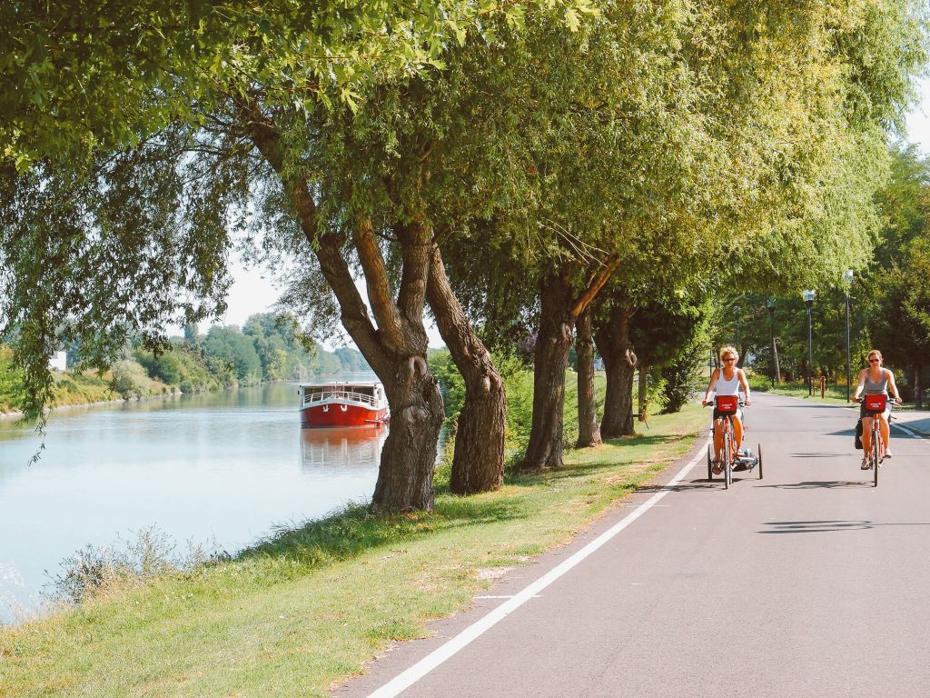 Two riders cruising the shaded towpath, Italy cycling holiday