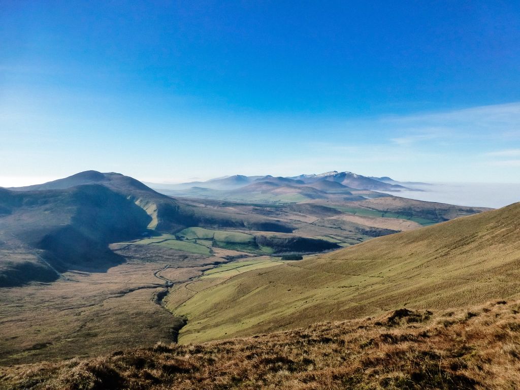 Paesaggio montuoso della Kerry Way con cielo blu e nuvole sparse.