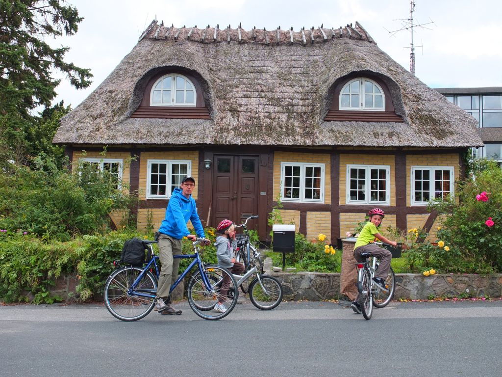 Famiglia in bici davanti a una casa tradizionale danese, vacanze in famiglia in bicicletta "Girolibero"