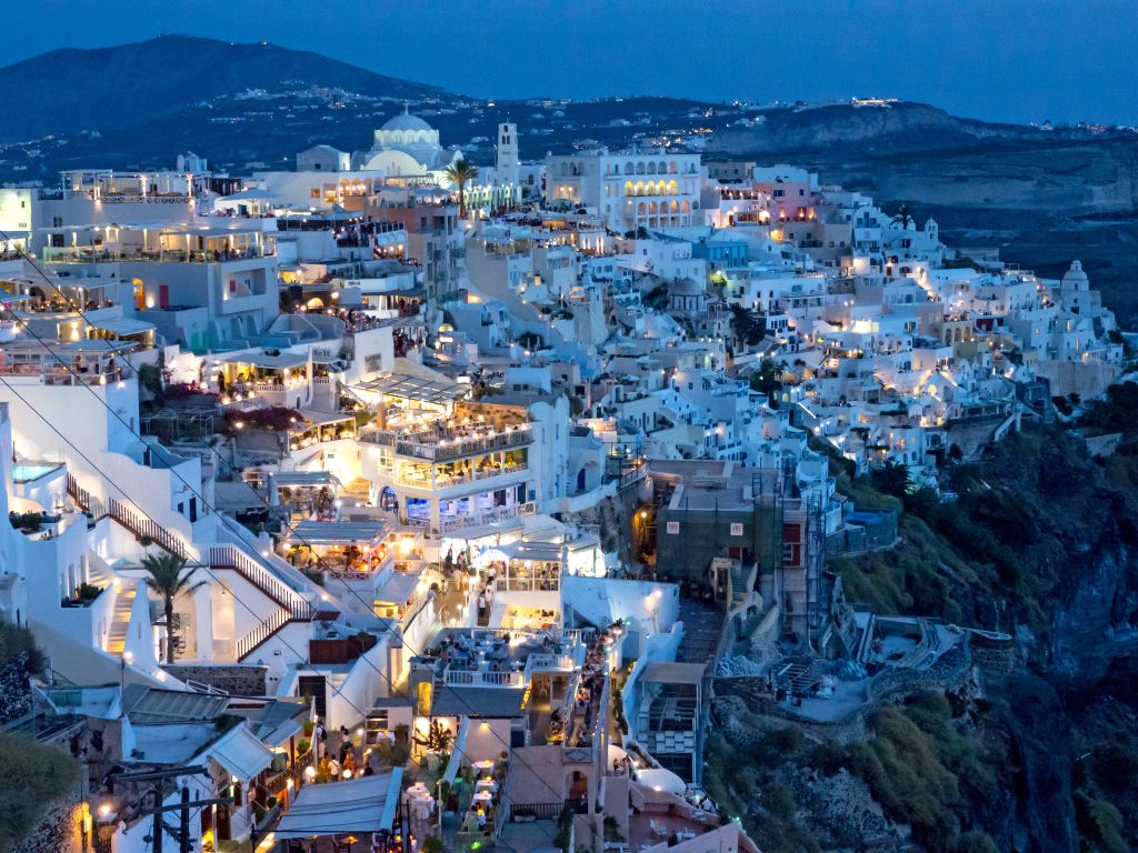 Vista panoramica su Oia al tramonto, con case bianche e il mare sullo sfondo, Santorini, Grecia.