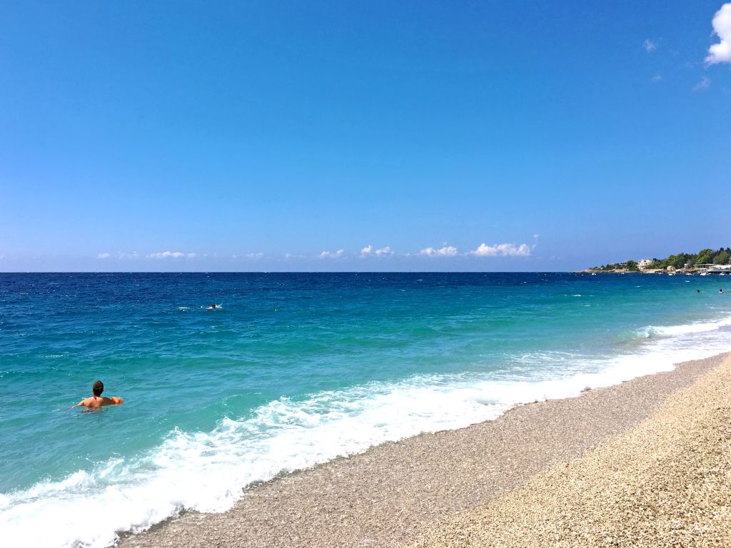 Spiaggia con mare azzurro e colline in lontananza lungo la costa albanese.