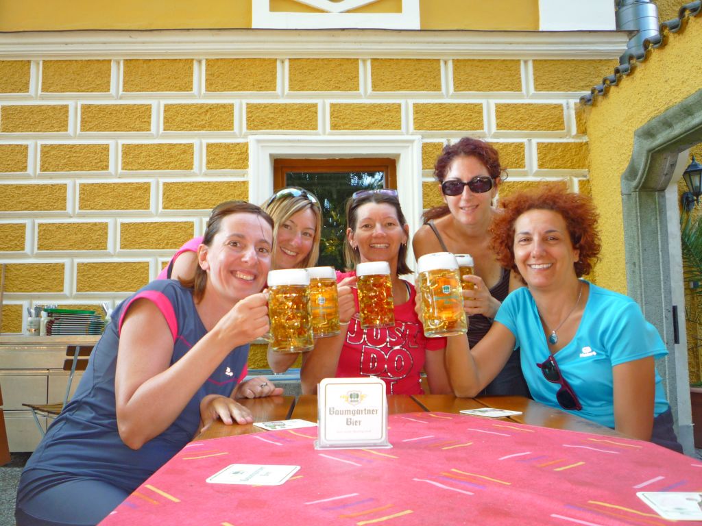 Gruppo sorridente di amiche brinda con una birra alla fine della tappa in bici di giornata, vacanze in bici Austria