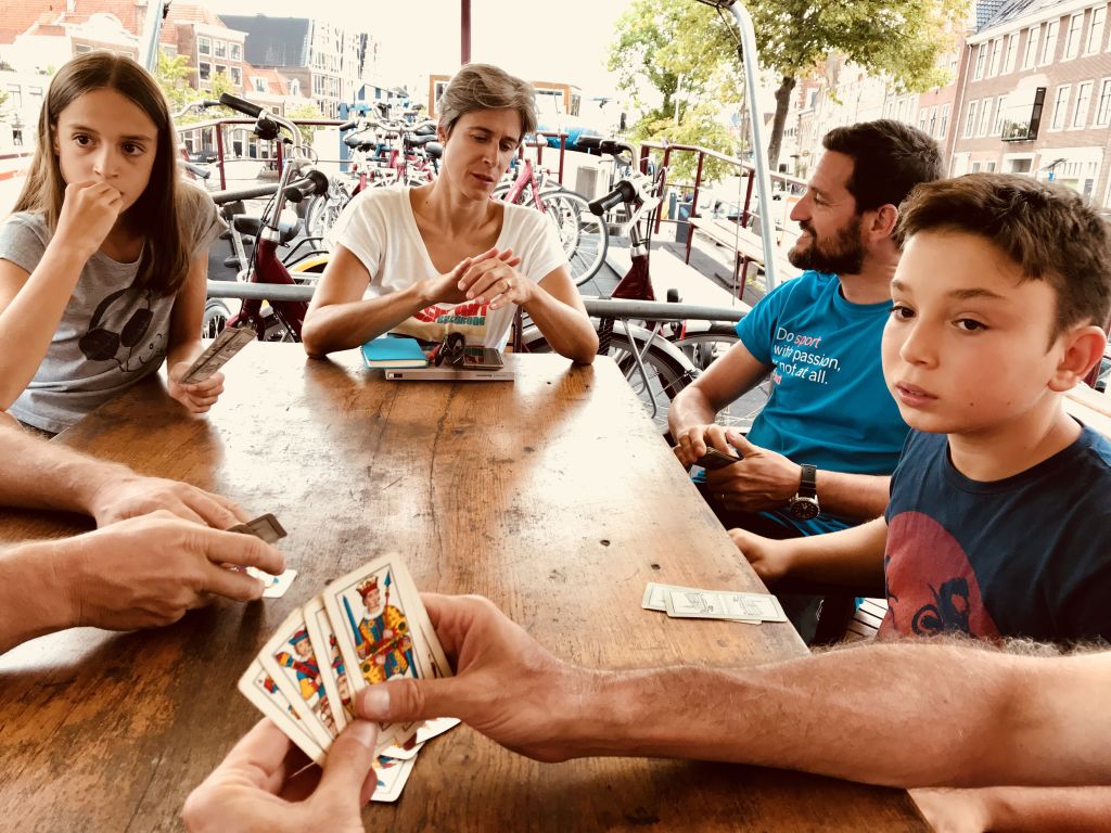 Eine Familie spielt Karten an einem Holztisch in einer entspannten und geselligen Szene.