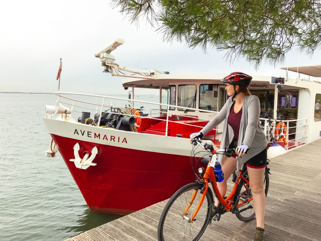Girl on bike posing in front of the Ave Maria boat