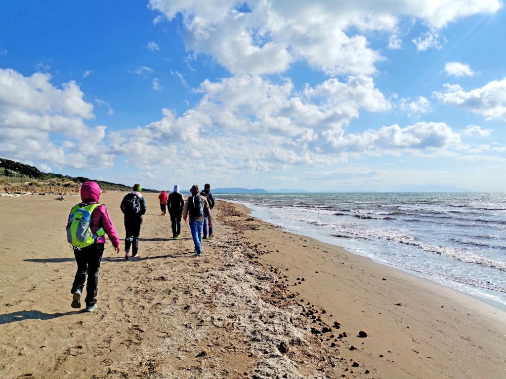 Escursionisti che camminano sulla spiaggia in una bella giornata con cielo azzurro, Costa degli Etruschi, Toscana.
