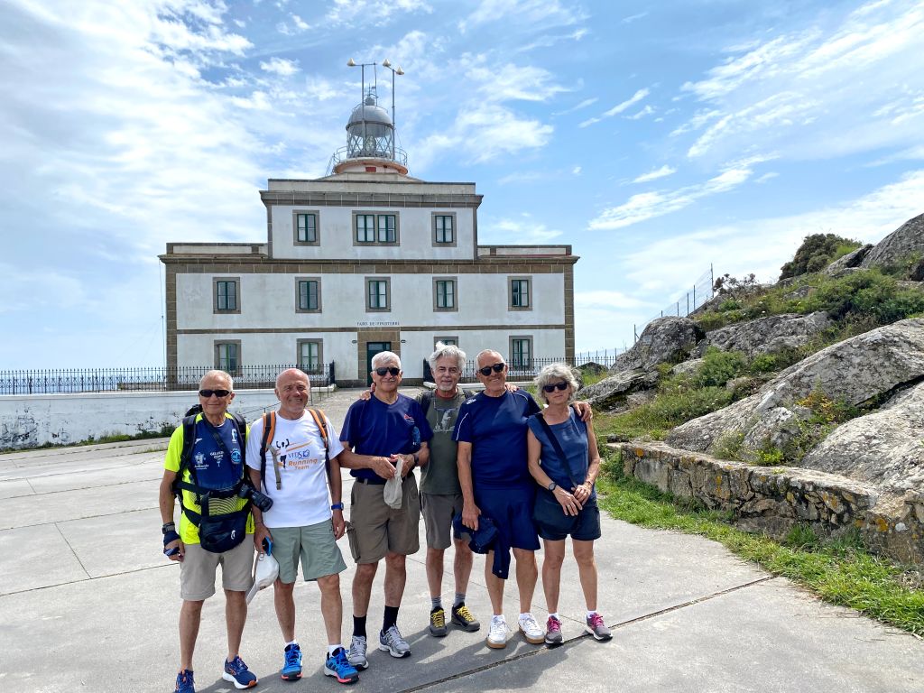 Gruppo di pellegrini in posa davanti al faro di Finisterre