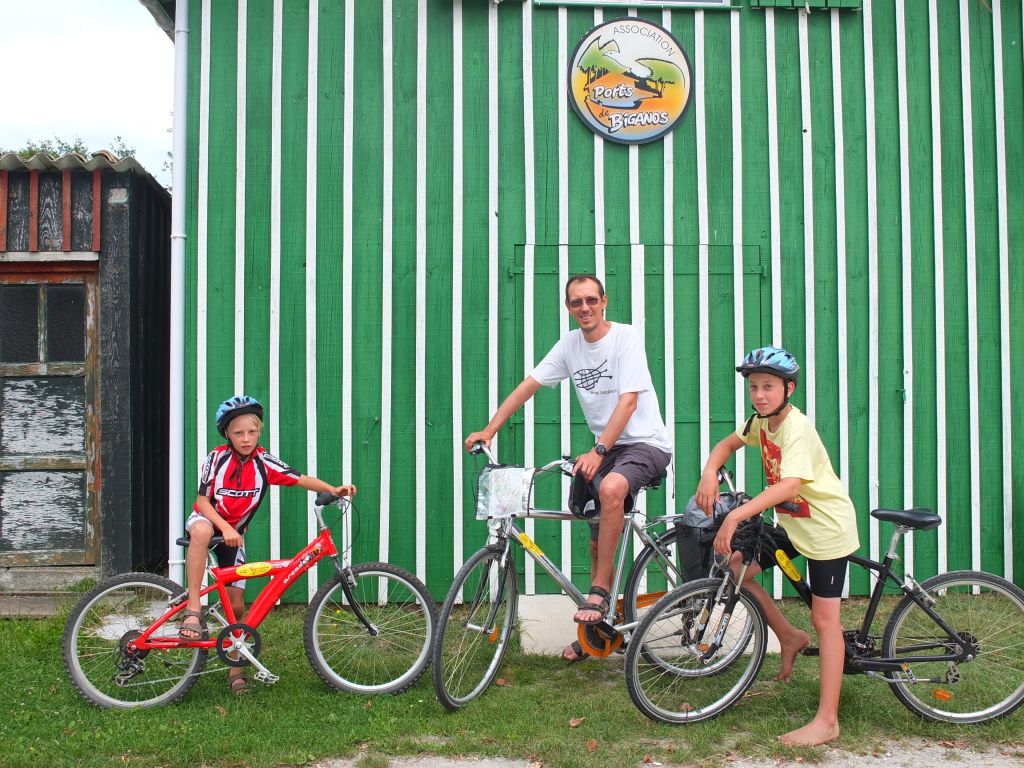 Famiglia durante un viaggio in bici Girolibero davanti a una tipica casa verde a righe, baia di Arcachon.