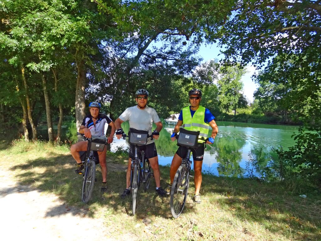 Gruppo di ciclo escursionisti in pausa all'ombra di alberi vicino al fiume, Francia in bicicletta